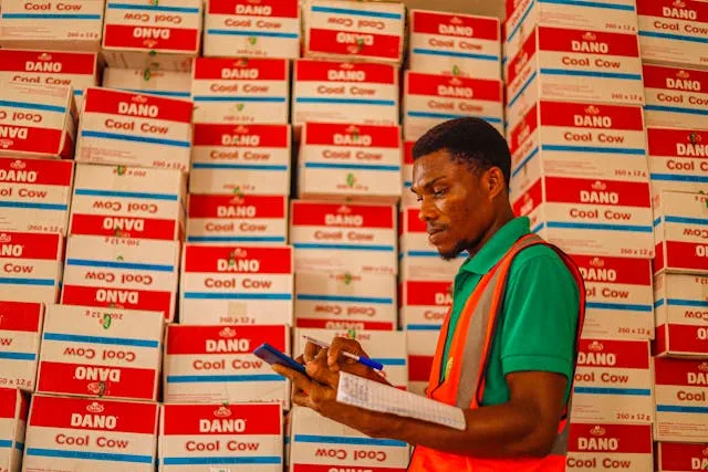 Warehouse supervisor with a clipboard auditing stacked inventory boxes