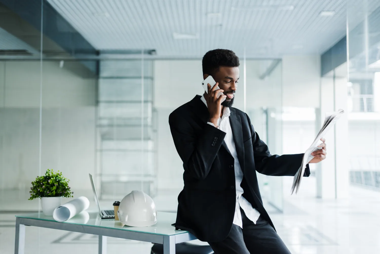 Smiling businessman talking on the phone while holding a newspaper