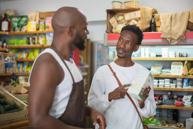 Shopkeeper advising a customer on a product in a small retail store